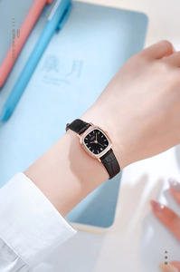 Elegant lady's rose gold square watch with black leather strap on a wrist in life setting