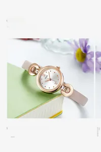 Montre élégante pour femme en or rose avec bracelet en cuir rose sur un livre