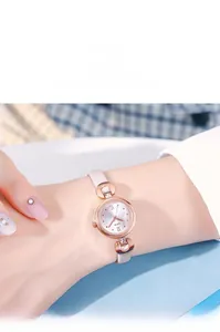 Gros plan d'une montre à quartz rose doré pour femme avec bracelet blanc et détails en cristal