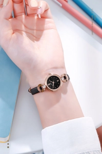 Montre femme élégante en or rose avec cadran noir et bracelet cuir portée au poignet