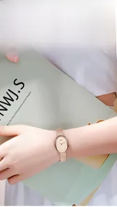 Détail d'une montre ovale en or rose avec index diamant et bracelet en métal ondulé