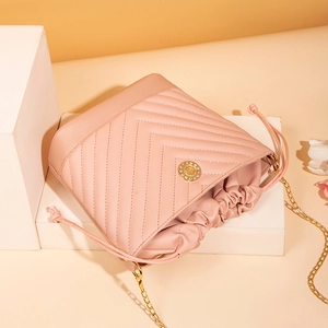 Sac seau matelassé rose avec logo soleil doré et bandoulière en chaîne métallique