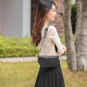 Quilted black waist bag with embroidered wide strap in outdoor fashion lifestyle setting