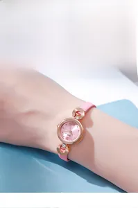 Gros plan d'une montre en cuir rose avec boîtier doré rose portée par un mannequin