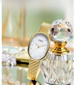 Vue détaillée du cadran ovale en nacre avec cristaux et bracelet à chaîne dorée luxe