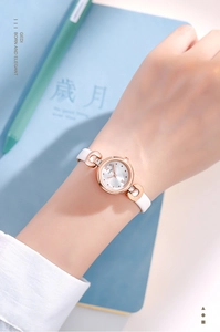 Gros plan d'une montre femme minimaliste or rose avec bracelet en cuir blanc fin