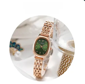 Détail d'une montre ovale au cadran vert avec bracelet en maille or rose et perles
