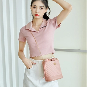 Sac seau matelassé rose avec cordon et chaîne dorée porté par un mannequin de mode