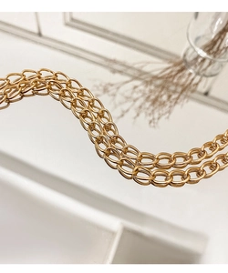 Macro shot of high-shine gold double-layer metal chain straps for a luxury handbag