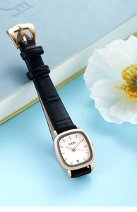 Detail of elegant square rose gold watch with black leather strap and date display