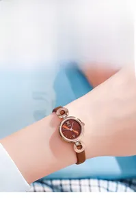 Gros plan d'une montre en or rose avec cadran marron et bracelet fin en cuir de qualité