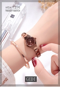 Gros plan d'une montre bracelet en or rose avec cadran marron sur un poignet féminin