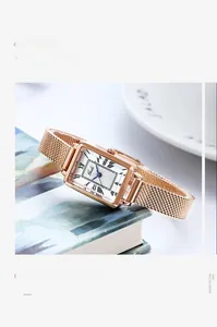 Détail de montre carrée pour femme en or rose avec bracelet milanais et cadran blanc
