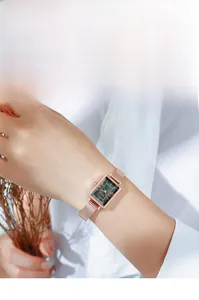 Détail d'une montre carrée vintage avec cadran vert et bracelet en maille rose doré