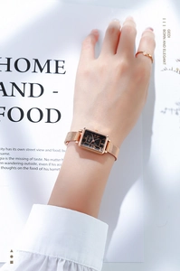 Gros plan d'une montre carrée pour femme avec cadran noir et bracelet milanais en or rose