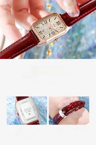 Detail view of rectangular rose gold watch with rhinestone dial and burgundy leather strap