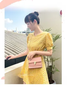 Sac à main rose matelassé avec chaîne dorée porté par un mannequin en robe jaune