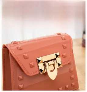 Detailed view of leaf lock gold hardware and square studs on coral jelly mini bag