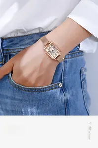 Détail de montre rectangulaire en or rose avec chiffres romains sur cadran