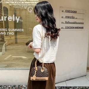 Retro shell-shaped handbag with vintage print pattern and metal chain strap outdoors