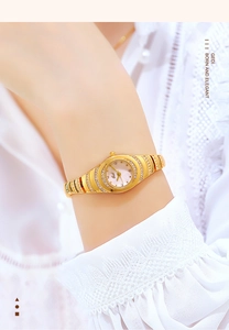 Detail of gold vintage jewelry watch featuring crystal inlay on bracelet and oval white dial