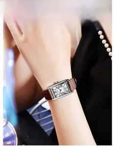 Close-up of rectangular silver watch with blue Roman numerals and brown leather strap