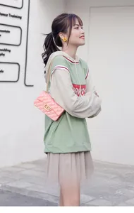 Vue de rue extérieure d'un mini sac matelassé rose clair avec une chaîne dorée