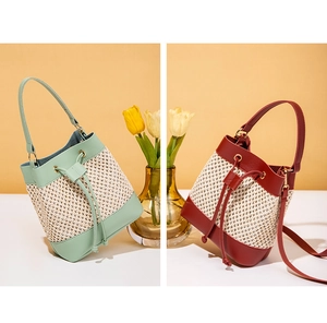 Detail of woven straw bucket bag with green and red faux leather panels and drawstring