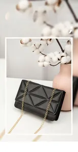 Close-up of black PU leather shoulder bag with geometric quilting and gold chain