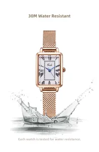 Détail d'une montre carrée en or rose avec chiffres romains et effet d'éclaboussure