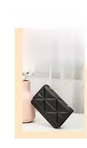Detail view of black quilted crossbody bag with matte finish and gold chain strap