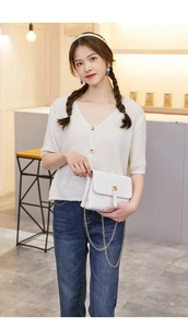 Minimalist white leather crossbody bag with gold chain strap shown on female model
