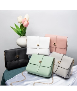 Five assorted colors of crossbody chain bags displayed with tulips and satin fabric