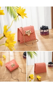 Detailed view of coral pink PVC jelly handbag featuring gold pyramid studs and chain strap
