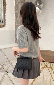 Modern black quilted crossbody bag with gold chain strap shown on model for sizing