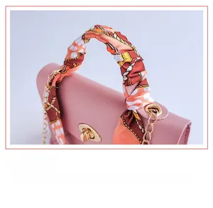 Detail of pink quilted leather bag featuring silk scarf handle and gold twist lock