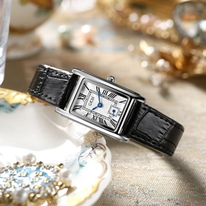 Macro detail of silver rectangular watch dial with Roman numerals and blue hands