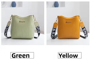 Détail de sacs seaux à motif crocodile vert et jaune avec bandoulières imprimées
