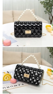 Detail of black quilted jelly bag with pearl handle and golden chain strap