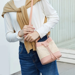 Pink leather and straw woven bucket bag for women with drawstring and gold metal buckles