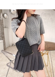 Detail of a black quilted shoulder bag featuring fine stitching and metal zipper closure