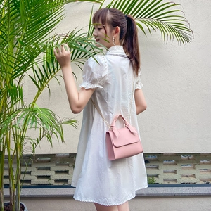 Pink leather small square bag with top handle and gold chain strap on female model