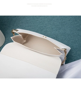Detail of white quilted crossbody bag showing gold chain strap and interior lining