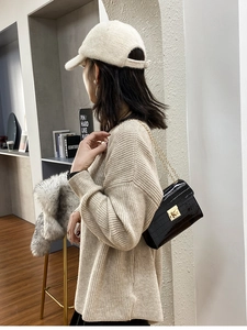 Detail of glossy black crocodile embossed crossbody bag with golden chain and lock