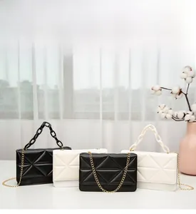Detailed view of diamond-quilted flap bags with gold chain straps in black and cream