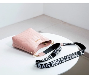 Détail d'un sac seau rose à motif crocodile avec bandoulière large en tissu imprimé