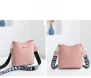 Vue détaillée du sac seau rose motif crocodile avec large bandoulière lettrée