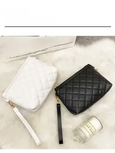 Detail of quilted rhombic clutch bags in black and white with gold metal hardware