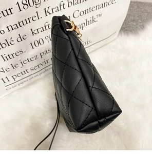 Close-up of quilted black crossbody bag with premium gold chain hardware and stitching