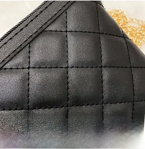 Macro shot of black quilted faux leather handbag with gold chain strap detail